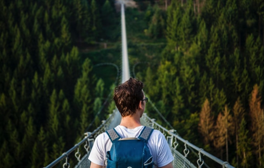 man with backpack hiking on big with tripod